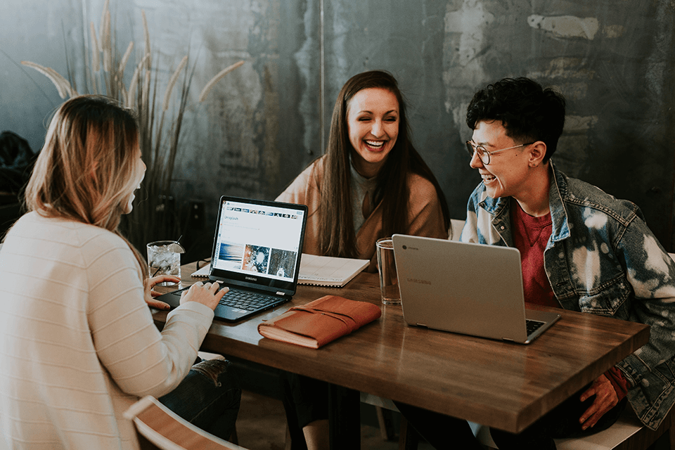 Group of women sitting around a work table smiling and laughing