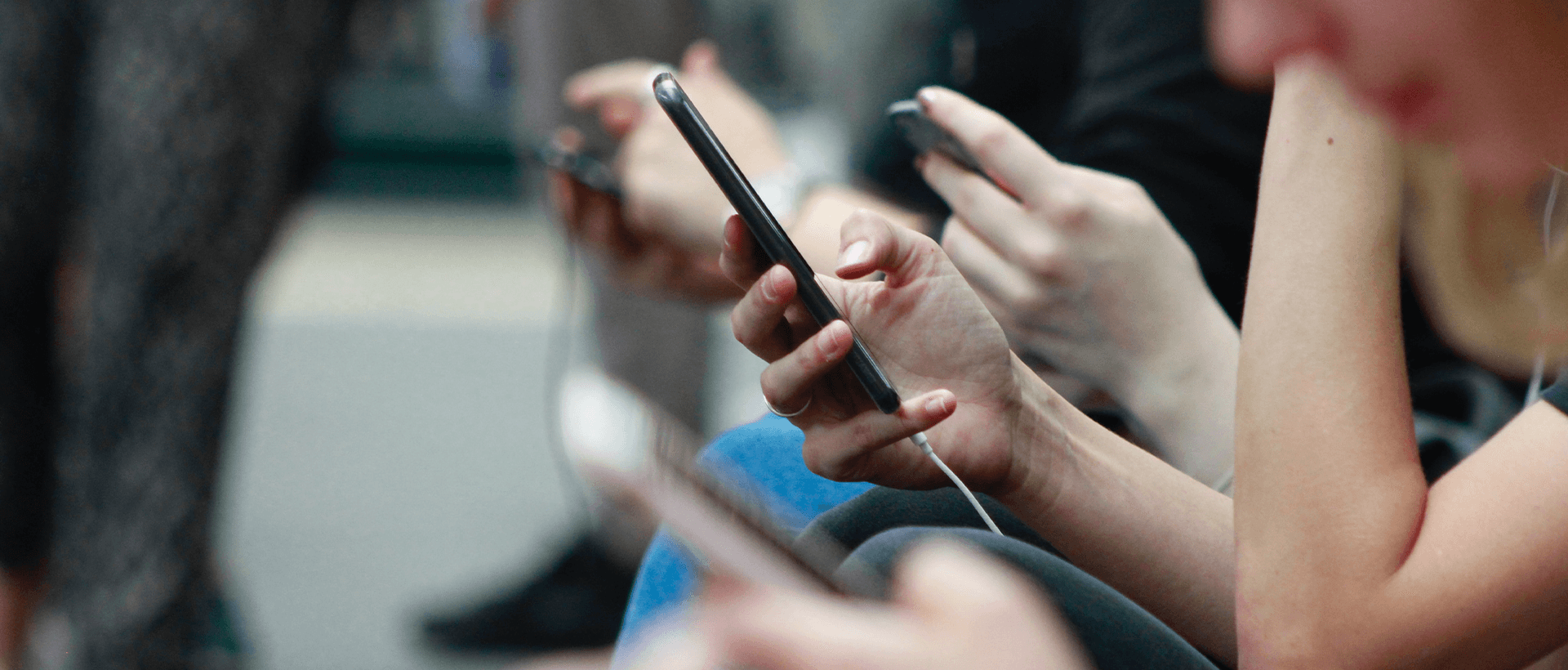 a group of people sitting next to each other using cell phones.