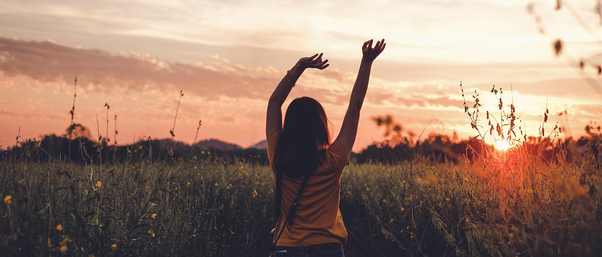 a woman standing in a field with her arms up.